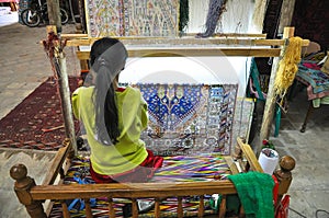 Young woman weaves a carpet on handloom