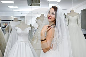 Young woman in wedding dress and veil in bridal shop