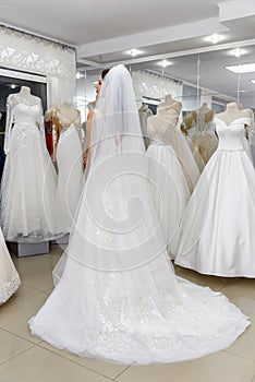 Young woman in wedding dress and veil in bridal shop