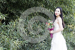 A young woman wedding photo/portrait stand by bamboos