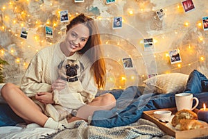 Young woman weekend at home decorated bedroom hugging a dog