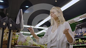 Young Woman Weighing Apples on the Electronic Scales. Housewife Shopping in a Supermarket in the Department of Fruit and