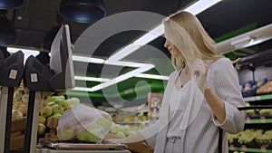 Young Woman Weighing Apples on the Electronic Scales. Housewife Shopping in a Supermarket in the Department of Fruit and