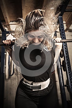 Young woman weight training in a gritty basement gym
