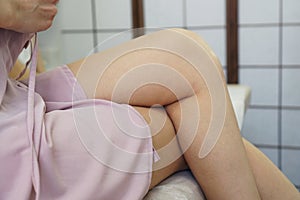 Young woman with a well-groomed body sits with smooth silky legs after waxing