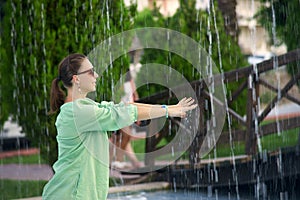 Young woman wets his hands in the fountain