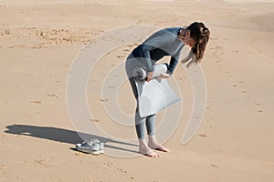 Young woman in wetsuit doing push ups on the beach.