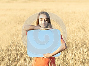 Young woman in the wheat field, holding mirror glass where reflected the blue sky. Meditation, mental health concept