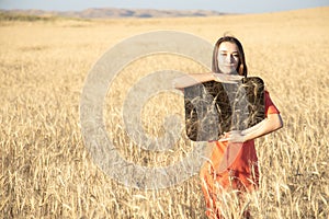 Young woman in the wheat field, holding mirror glass where reflected the dry grass. Meditation, mental health concept