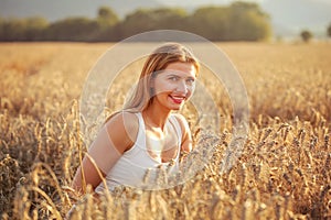 Young woman in wheat field lit by afternoon sun.