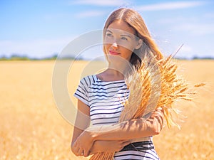 Young woman at the wheat field under the blue sky at the sunny day