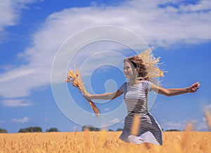 Young woman at the wheat field under the blue sky at the sunny day