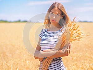 Young woman at the wheat field under the blue sky at the sunny day