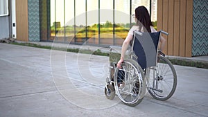 Young woman in a wheelchair. A girl rides in a wheelchair against the background of a glass building. Special transport