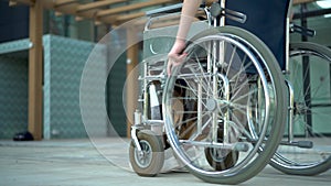 Young woman in a wheelchair. A girl rides in a wheelchair close-up hand. Special transport for the disabled.