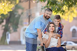 Young woman in wheelchair with her family walking outdoors