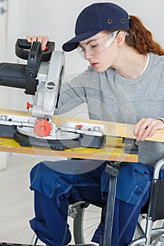 Young woman in wheelchair using circular saw