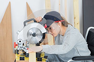 young woman in wheelchair using circular saw