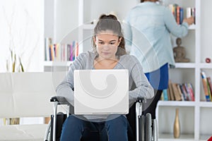 Young woman on wheelchair using laptop