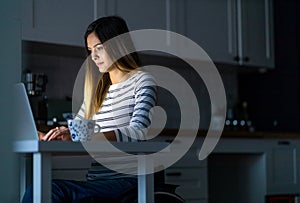 Young woman in wheelchair working on laptop till late