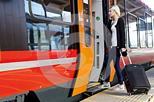 Young Woman With Wheeled Luggage Boarding Train