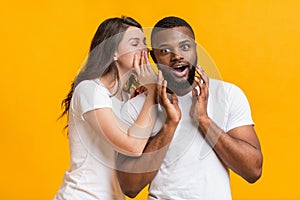 Young Woman Whispering Gossips Into Her Black Boyfriend`s Ear