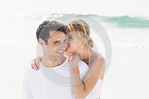 Young woman whispering in mans ears on the beach