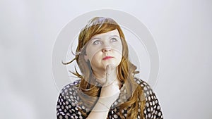 A young woman on a white background shows an emotion of thoughtfulness