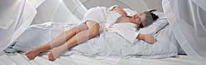Young Woman in White Bathrobe on White Bed