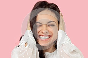 Young woman in a white blouse closing her ears