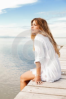 Young woman in white clothes on a pier