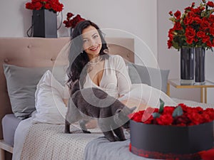young woman in white dres is sitting on bed.