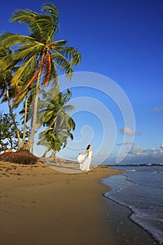 Young woman in white dress on a beach