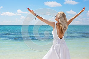 Young woman in white dress enjoying summer day on the beach