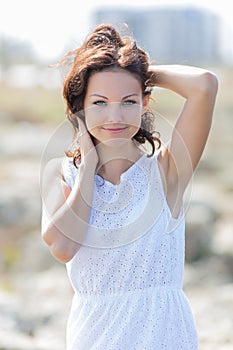 Young woman in white dress poses with hands on head