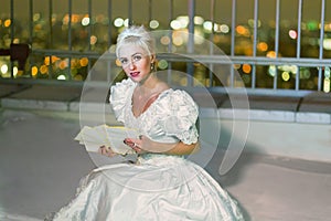 Young woman in white dress sits on snowy high-rise photo