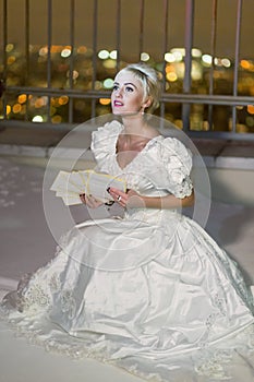 Young woman in white dress sits on snowy high-rise photo