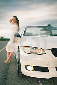 Young woman with white dress standing at the white car