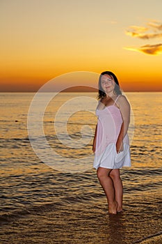 Mujer joven en blanco ropa bastidores sobre el costa sobre el atardecer 