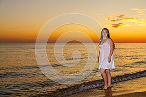 Mujer joven en blanco ropa bastidores sobre el costa sobre el atardecer 