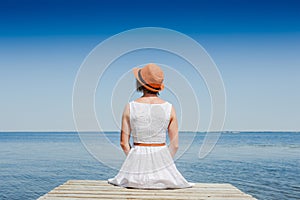 Young woman in white dress sunbathing at the seaside