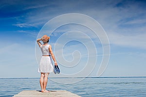 Young woman in white dress sunbathing at the seaside