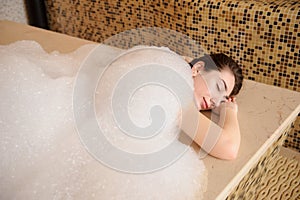 young woman in white foam relaxing in a hamam