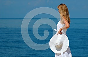 Young woman with white hat looks at sea