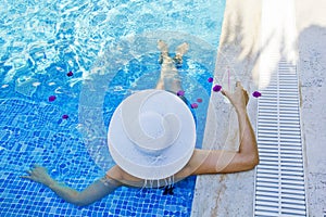 Young woman in a white hat relaxing in the pool