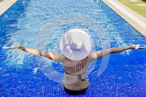 Young woman in a white hat relaxing in the pool