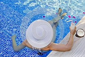 Young woman in a white hat relaxing in the pool