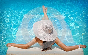 Young woman in white hat resting in pool