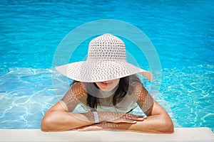 Young woman in white hat resting in pool