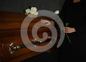 Young woman with white rose near  in funeral home, closeup